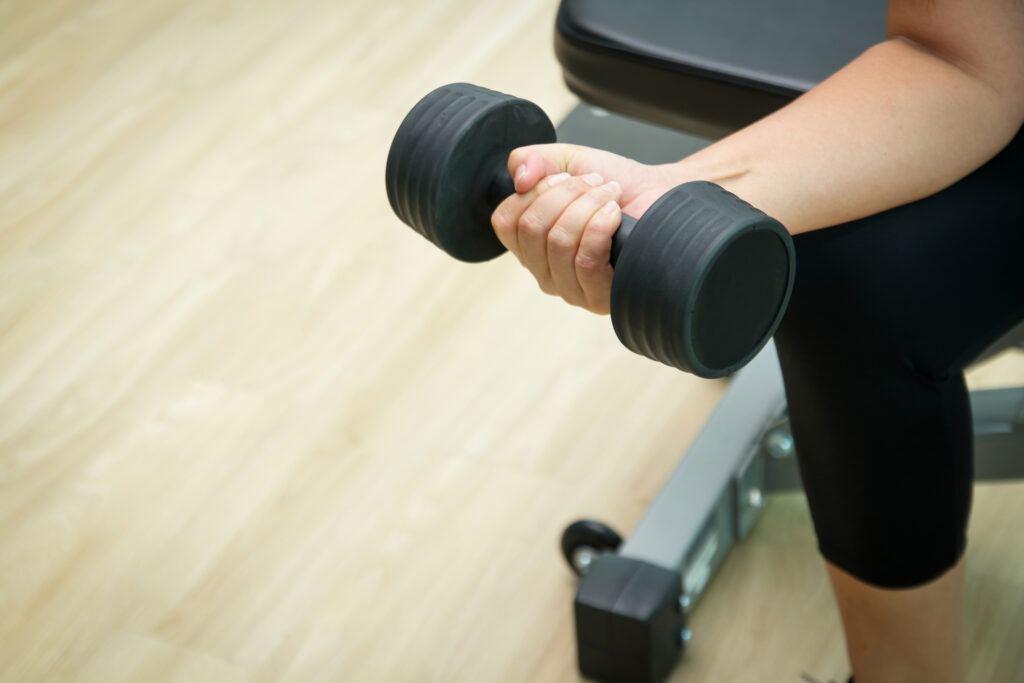 Midlife woman performing strength training with a dumbbell, highlighting muscle maintenance and resistance exercise during menopause.