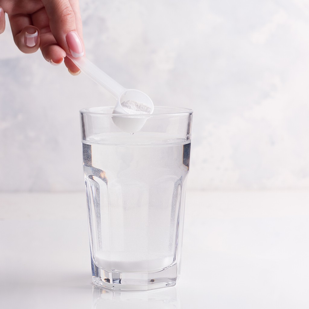 Creatine monohydrate powder being mixed into a glass of water — simple and effective daily supplement routine for women’s muscle, bone, and brain health.