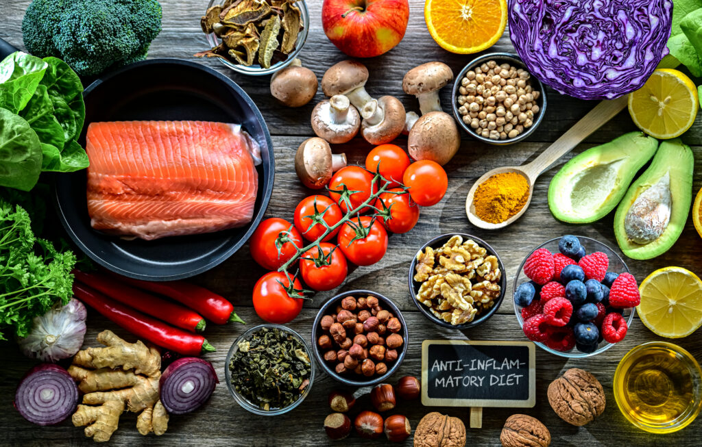 Foods commonly included in an anti-inflammatory eating pattern, including salmon, vegetables, berries, nuts and olive oil
