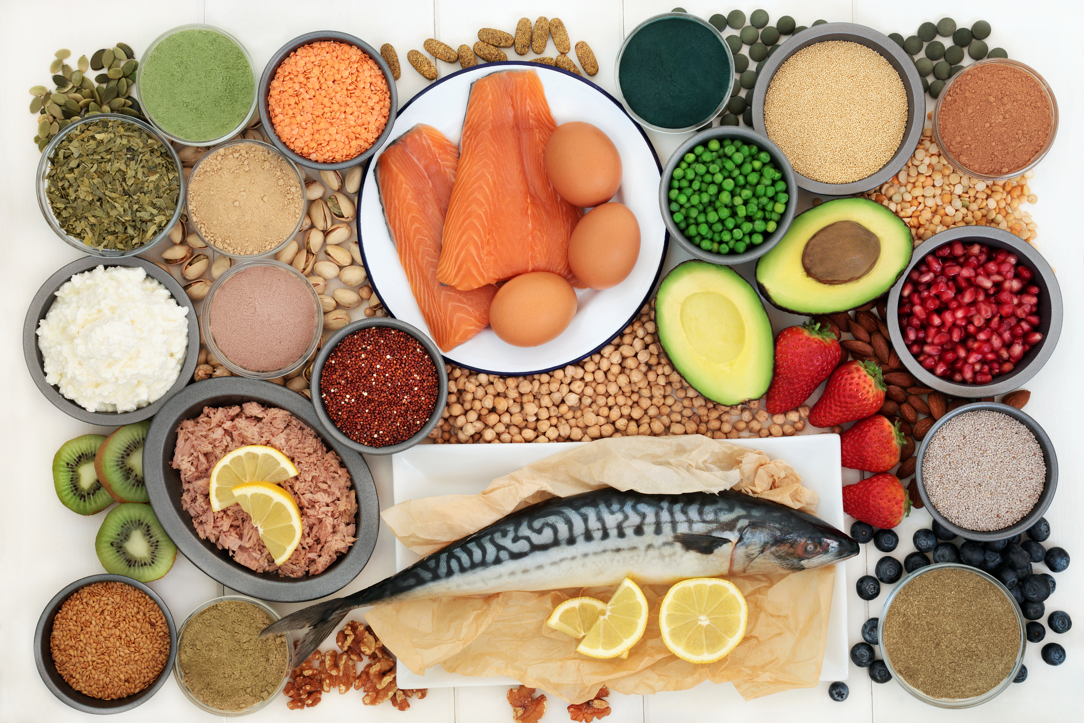 Selection of protein-rich and fibre-rich foods, including fish, eggs, legumes, nuts, seeds and fruit, illustrating nutrients that help support fullness and satisfaction during menopause